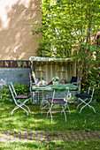 Gartentisch und Strandkorb im sommerlichen Garten hinterm Haus