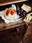 Käse, Cracker und Weintraube auf rustikalem Tisch