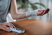 Senior woman doing wrist physical therapy with TENS