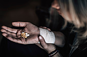 Suicidal woman holding number of pills in hand
