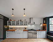 Classic kitchen in white with glass-fronted wall units and gas cooker