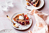 Cherry clafoutis served on plates with creme fraiche and fresh cherries.