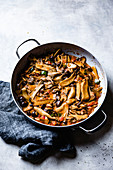 Sliced mushrooms and peppers sauteed in a pan.