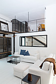 Wohnbereich mit weißen Sofas und Blick auf Galerie in Loft im Industriestil