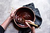 Chocolate ganache mixed in a bowl by a hand held whisk.