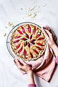 Rhubarb cake in a hand held baking dish being placed on a cooling rack.