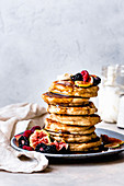 Ein Stapel glutenfreie Pancakes mit Joghurt, Ahornsirup und Früchten