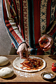 Preparing pizza: Brushing dough with tomato sauce