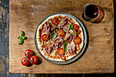Pizza Napoli mit Schinken und Tomaten serviert mit Rotwein