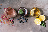 A trio of cocktails with rose petals, blueberries and lemons