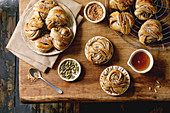 Traditional Swedish cardamom sweet buns Kanelbulle in plate, ingredients in ceramic bowl above on wooden table. Flat lay, space