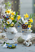 Small Easter bouquets in ostrich eggs as a vase: daffodils, horned violets, primroses, forget-me-nots and feathers
