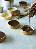 Schokoladencreme in Mürbeteig-Tarteletts füllen