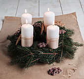 Handmade Advent wreath with fir branches, biscuits and white candles
