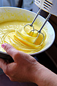 From above anonymous woman using mixer to prepare batter for pastry in kitchen at home