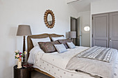 Circular mirror above double bed in farmhouse