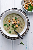 Vegan potato and basil cream soup with croutons and roasted sunflower seeds