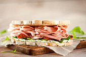 Ham sandwich on white bread, with tomato, arugula and creamy cheese dressing.