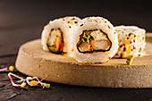 Sushi rolls filled with shrimp and cream cheese, covered with sesame seeds.