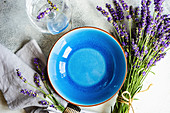 Summer time table set with blue stoneware and cutlery decorated with fresh lavender flowers