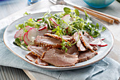 Thinly cut goose breast with radish and rocket salad