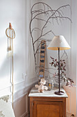 Lamp, branch and dried flowers on wooden cabinet in corner