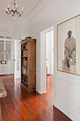 Artwork and bookcase in hallway with wooden floor