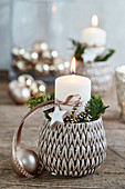 Wintry arrangement of candle and dried flowers in flower pot with structured surface