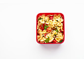 Nudelsalat mit Tomaten, Kapern und Basilikum in Lunchbox zum Mitnehmen