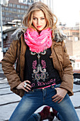Young blonde woman wearing jeans, jumper with motif and winter jacket