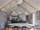 Large, round marble dining table and open-plan kitchen in living space on gallery