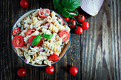 Pasta salad with basil, tomatoes, black olives, red onion and feta cheese