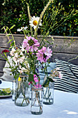 Wiesenblumen in Wassergläsern als sommerliche Tischdeko