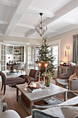 View across coffee table to Christmas tree in living room with coffered ceiling
