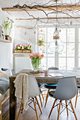 Graue Schalenstühle am Holztisch im Esszimmer mit Frühlingsdeko