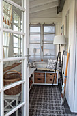 View into vestibule with white bench, sideboard and standard lamp