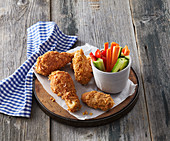 Breaded baked chicken drumsticks and chicken wings with vegetable sticks