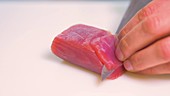 Chef slicing piece of fresh raw tuna