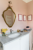 Antique gilt-framed mirror on pink wall in bathroom