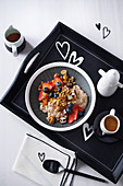 Crispy porridge with chocolate, fruits and maple syrup on a tray