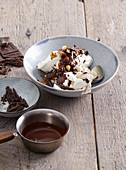 Baiser-Dessert mit Schokoladensauce, Schokoraspeln und Nüssen