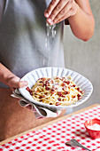 Frau serviert Spaghetti Carbonara mit Parmesan