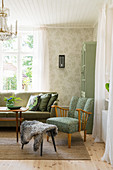 Green upholstered furniture and patterned wallpaper in living room