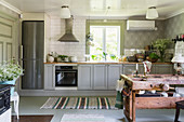 Grey cabinets in country-house kitchen with antique table in foreground