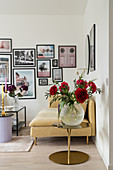 Glasvase mit roten Pfingstrosen, Sofa und Fotogalerie im Wohnzimmer