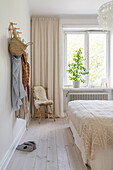 Double bed with crocheted bedspread, wooden peg rack and wooden chair with sheepskin