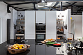 Kücheninsel mit schwarzer Hochglanz-Arbeitsplatte in offener Küche