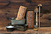 Selbstgebackene Brote mit Vintage-Küchenutensilien vor Holzhintergrund