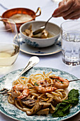 An outdoor table with pasta cacio e pepe (pasta with cheese and pepper), shrimp skewers with basil, artichokes and white wine
