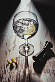 Glass of gin tonic in composition with lemon and jigger on table in dark room